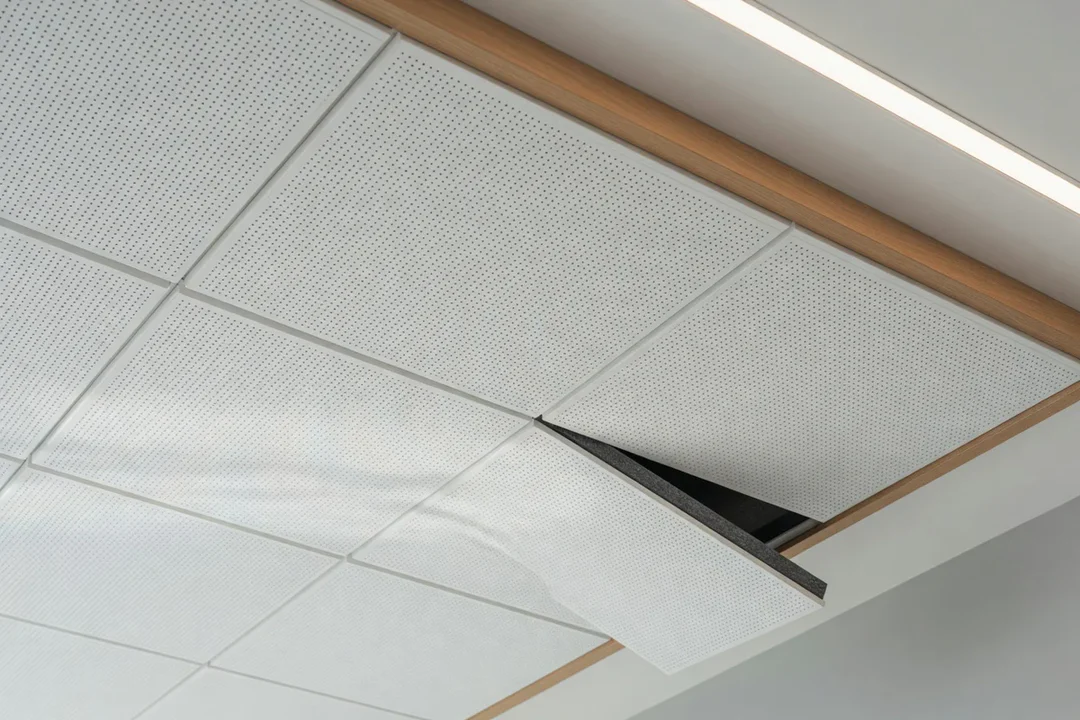 Plafond acoustique perforé moderne dans un intérieur professionnel avec panneaux blancs microperforés et éclairage architectu
